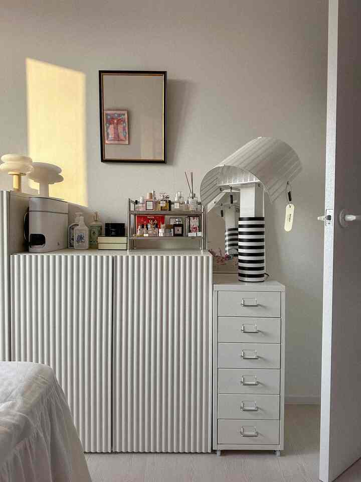 明るいホワイトトーンの狭い部屋、低い収納棚の上に鏡と化粧品が配置されたコンパクトな化粧台のある空間