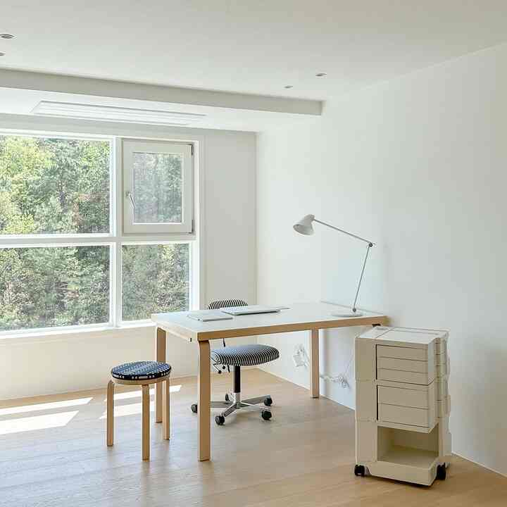 白とナチュラルカラーのホームオフィス、広い窓から自然光が入り、シンプルで清潔感のあるインテリア