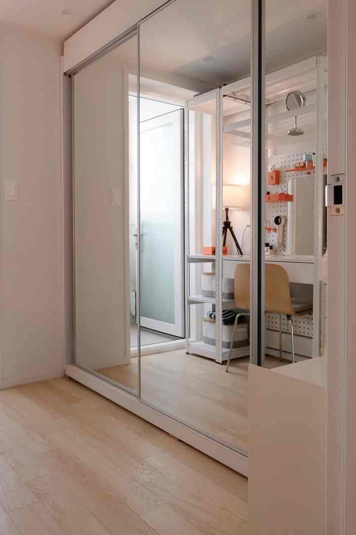 ホワイトと木目調の調和した玄関空間、スリムなシューキャビネットとデスクが配置されたシンプルでミニマルなインテリア