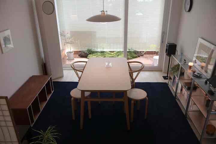 ネイビーカーペットと木目調家具が配置されたダイニングルーム、照明と植物が調和する雰囲気のある空間