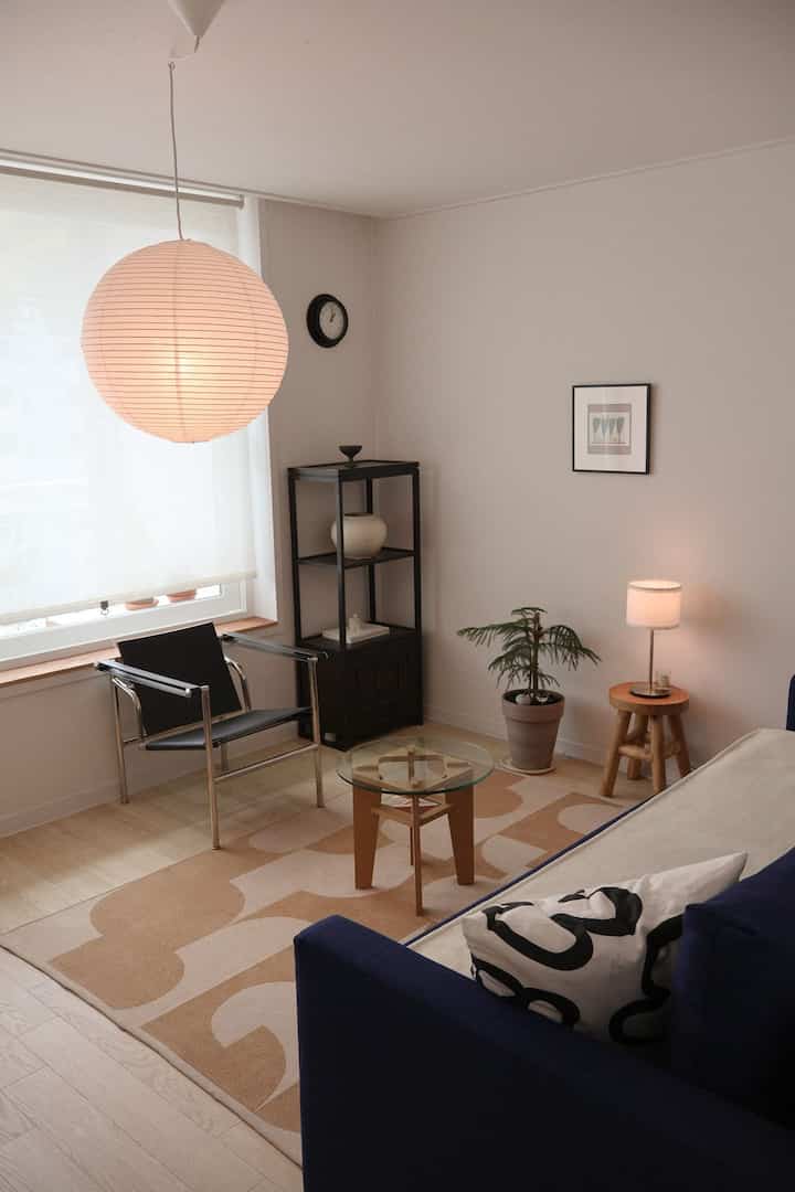 白とベージュのトーンのリビング、ネイビーのソファとガラスのコーヒーテーブル、シンプルで自然な雰囲気のインテリア