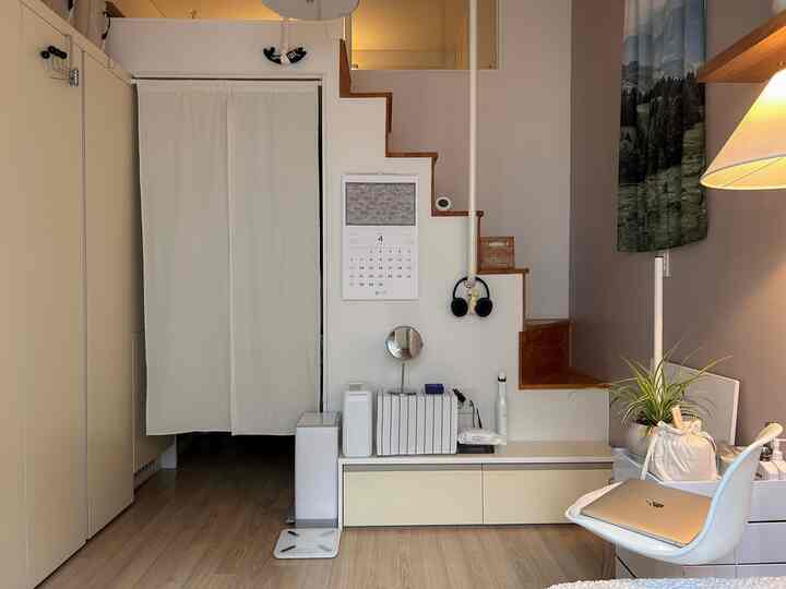 白とベージュのトーンの小さなロフト空間、デスクと階段が配置されたシンプルモダンな雰囲気のインテリア