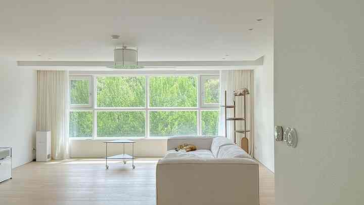 ホワイトとナチュラルカラーのリビング、大きな窓とコーナーソファ、キャットタワーが配置された落ち着いた空間