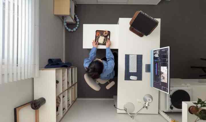 白とダークグレーの色調のコンパクトな一人暮らしホームオフィス、机とモニター、本棚が配置された整った作業空間