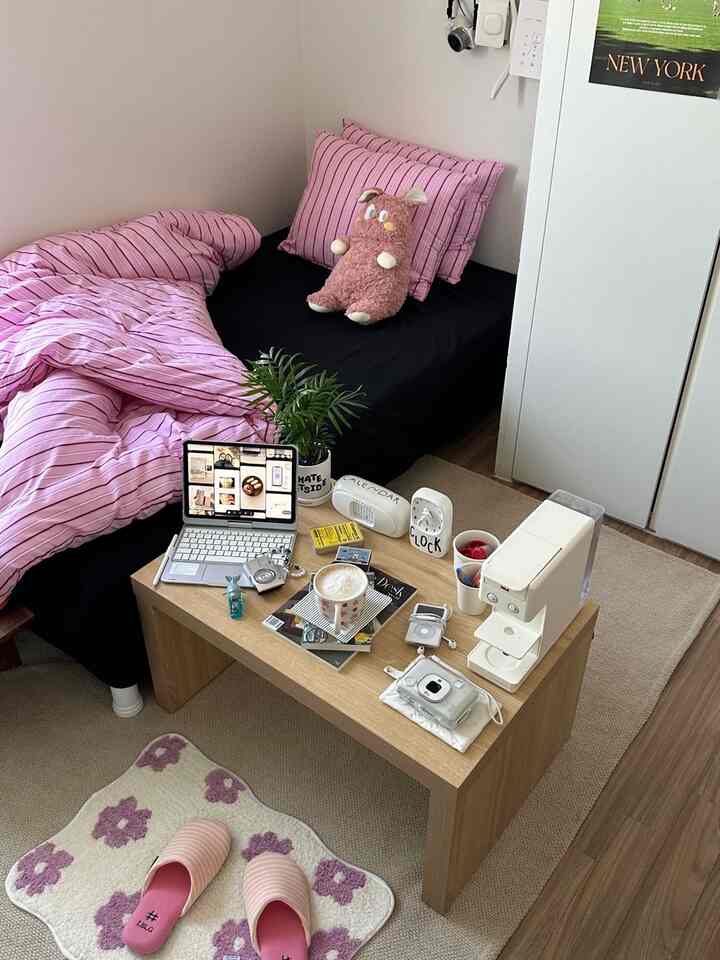 ピンクの寝具とナチュラルな木製ミニテーブルが配置されたシンプルモダンな寝室のインテリア