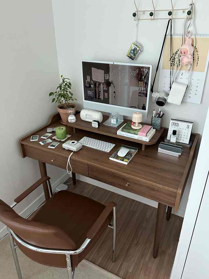 木目調と白が調和するホームオフィス、パソコンとキャンドル、本が整然と並ぶシンプルな作業空間