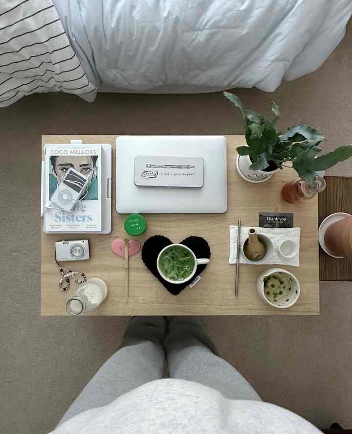 ナチュラルな木目調の寝室のローテーブルに茶器セットとノートパソコン、植物が配置された居心地の良いおうちカフェ