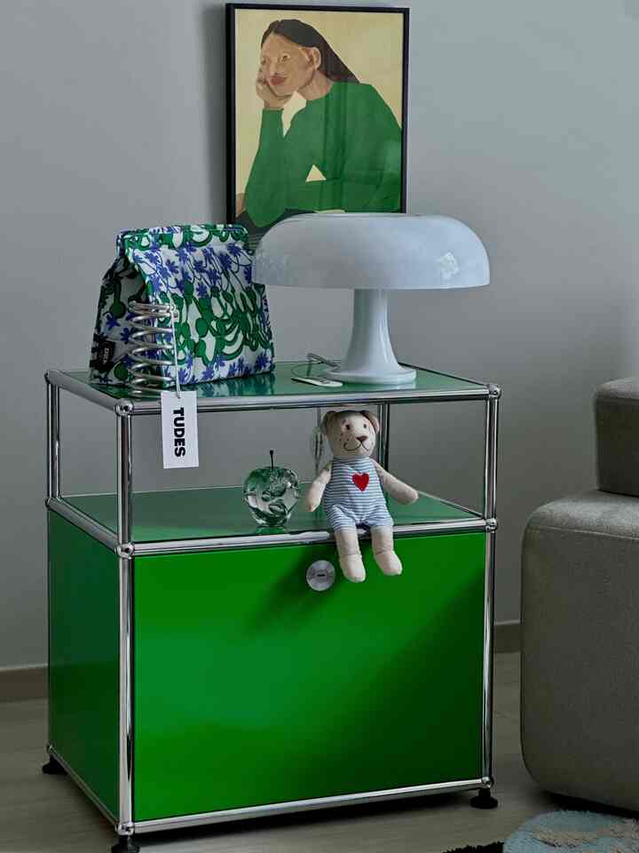 明るいグリーンのUSM収納ユニットの上に白いテーブルランプとぬいぐるみが置かれたシンプルなリビング用サイドテーブル