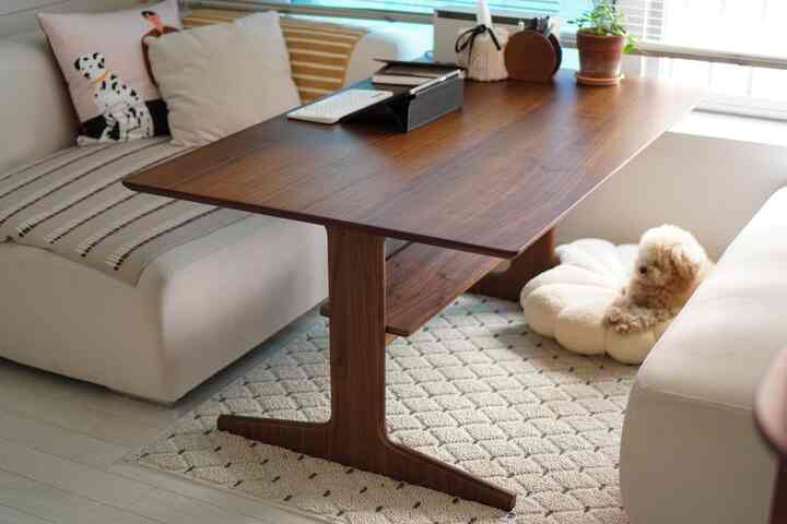 木目調とベージュのリビング、ソファとクルミ材のテーブル、犬用ベッドが配置された自然で落ち着いた雰囲気のインテリア