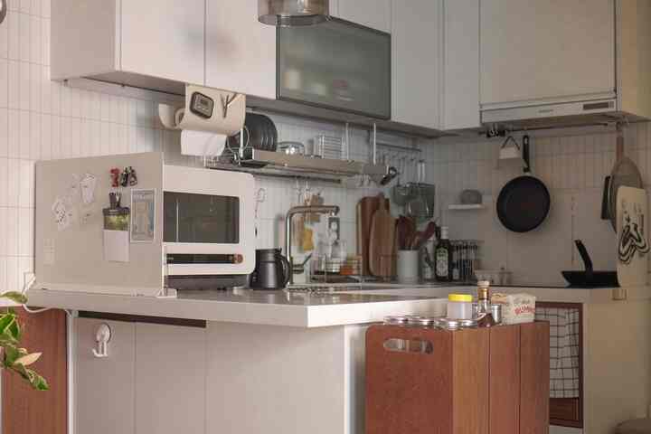 白と木目調が調和したキッチン、整頓された調理器具と収納アイデアが印象的な落ち着いた雰囲気のインテリア