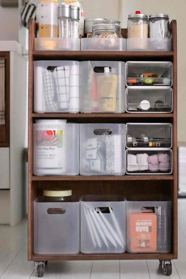 ホワイトとウッドトーンのキッチンパントリー、透明な収納容器が整然と配置されたコンパクトなキッチンワゴン