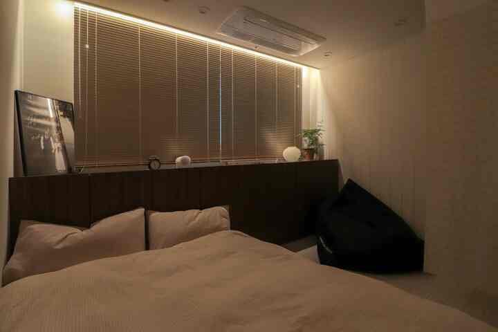 暖かみのあるベージュとブラウンの色調の寝室、ブラインドと収納が調和した安定感のある整った空間