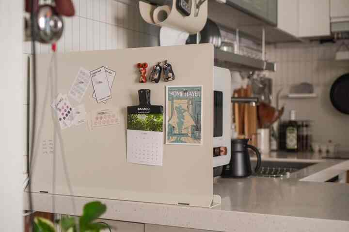 ベージュ色の金属パーティションとさまざまなキッチン用品が配置されたナチュラルなキッチン空間