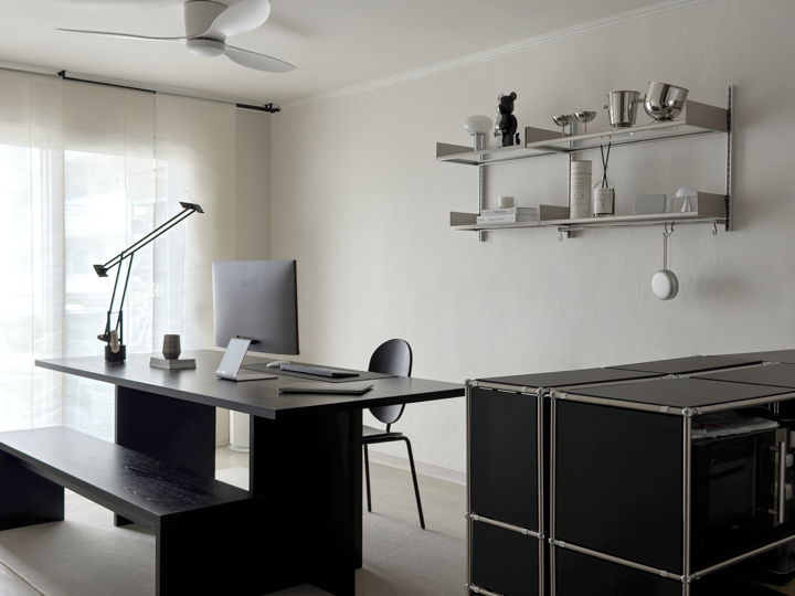 白と黒のトーンのホームオフィス、大きな黒いデスクとステンレス製システム棚が配置されたミニマルなモダン空間