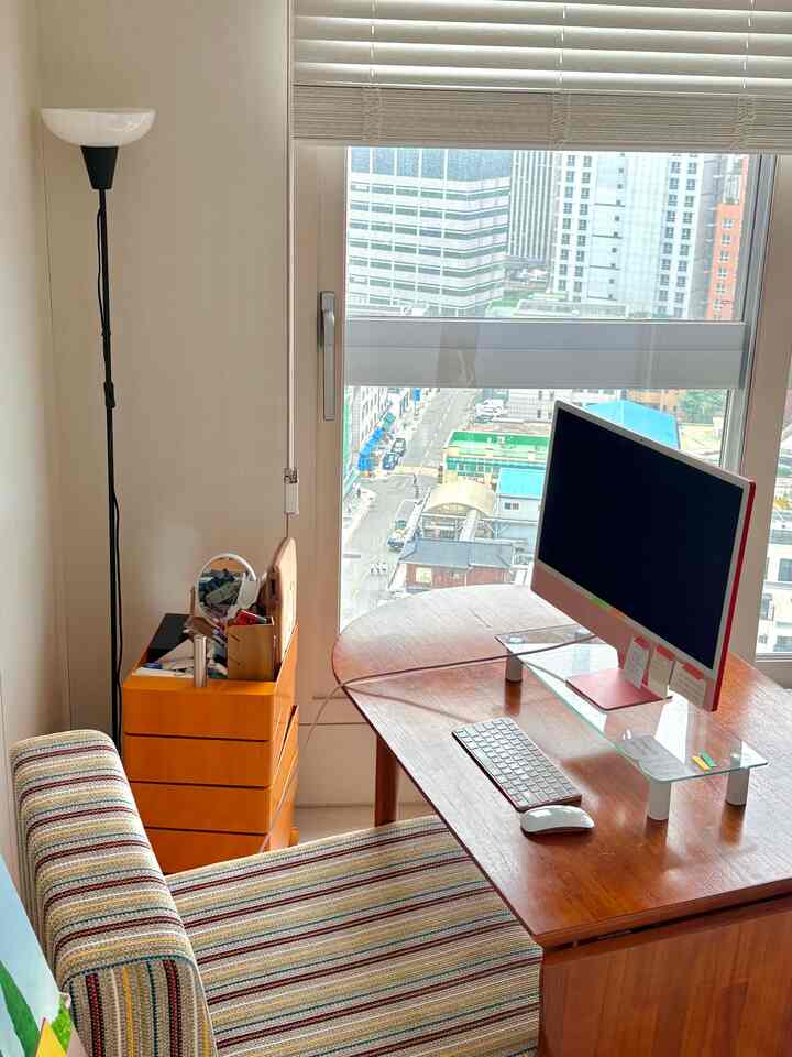 自然な木目調のホームオフィス、コンピューターモニターとデスク、ストライプのアームチェアが置かれた明るい雰囲気のインテリア