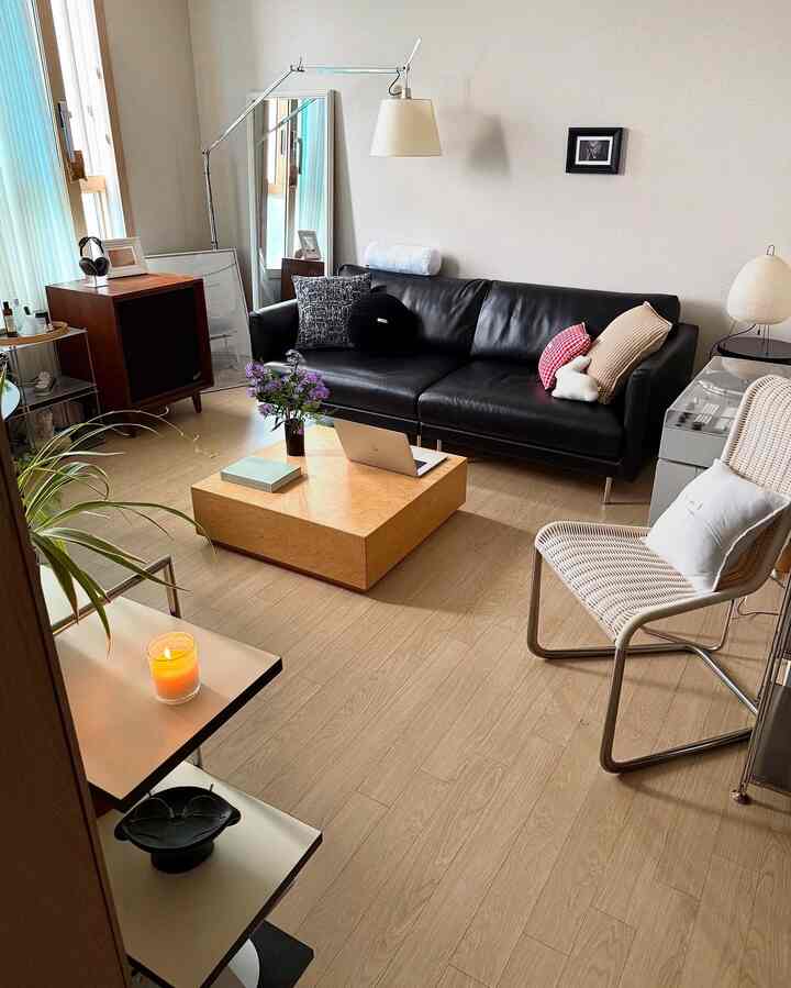 ナチュラルでモダンな雰囲気のリビング、ブラックレザーソファとライトブラウンの木製コーヒーテーブルが配置された印象的な空間