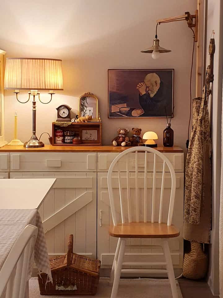 アイボリーと木目調の寝室ホームオフィス空間、ヴィンテージの額縁と温かみのある照明が調和したフレンチカントリースタイルのインテリア