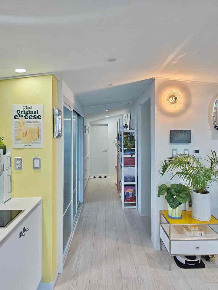 ホワイトとイエローが調和する廊下空間、本棚と植物が配置されたナチュラルでモダンなインテリア