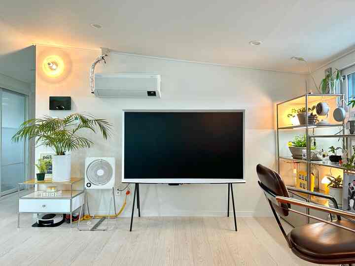 白とシルバーの色調のリビング、中央にテレビ、右側にシルバーメタルの棚が配置されたナチュラルモダンな空間