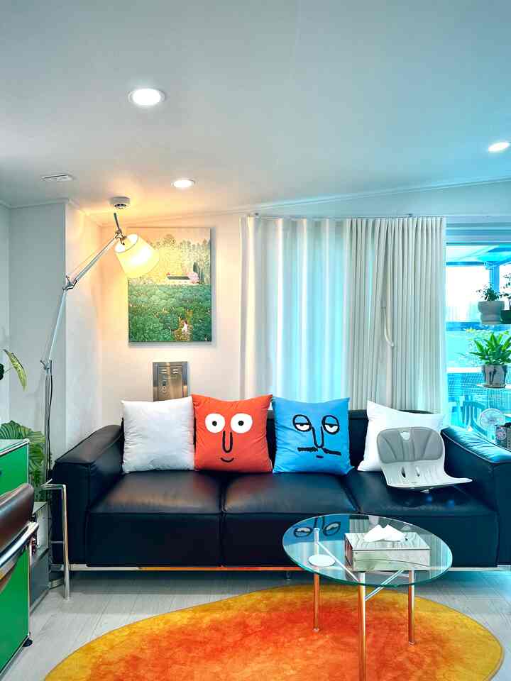 ブラックのソファとオレンジのラグが配置された、落ち着いた雰囲気のコンパクトなリビング