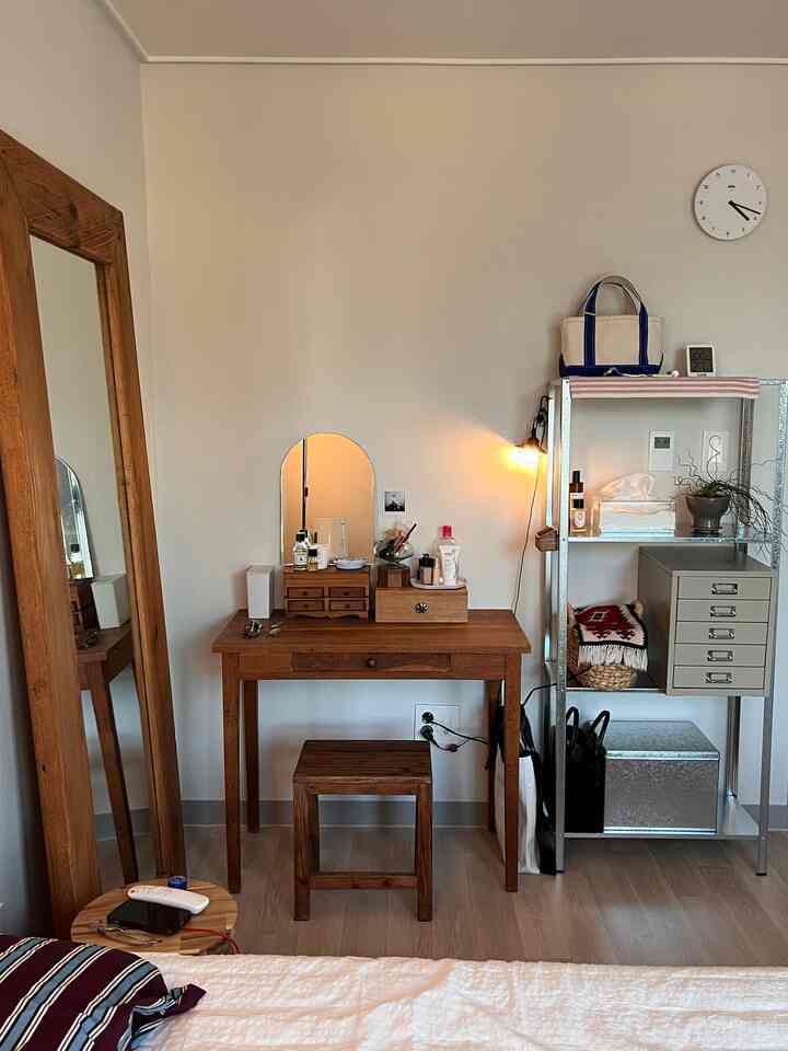 木目調とホワイトの寝室空間、木製デスクとスツール、収納棚と照明が配置された温かみのあるインテリア