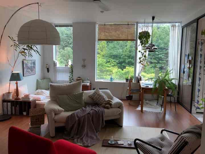 白と茶色のトーンのナチュラルモダンなリビングと書斎、ソファと机、植物が配置された印象的な空間