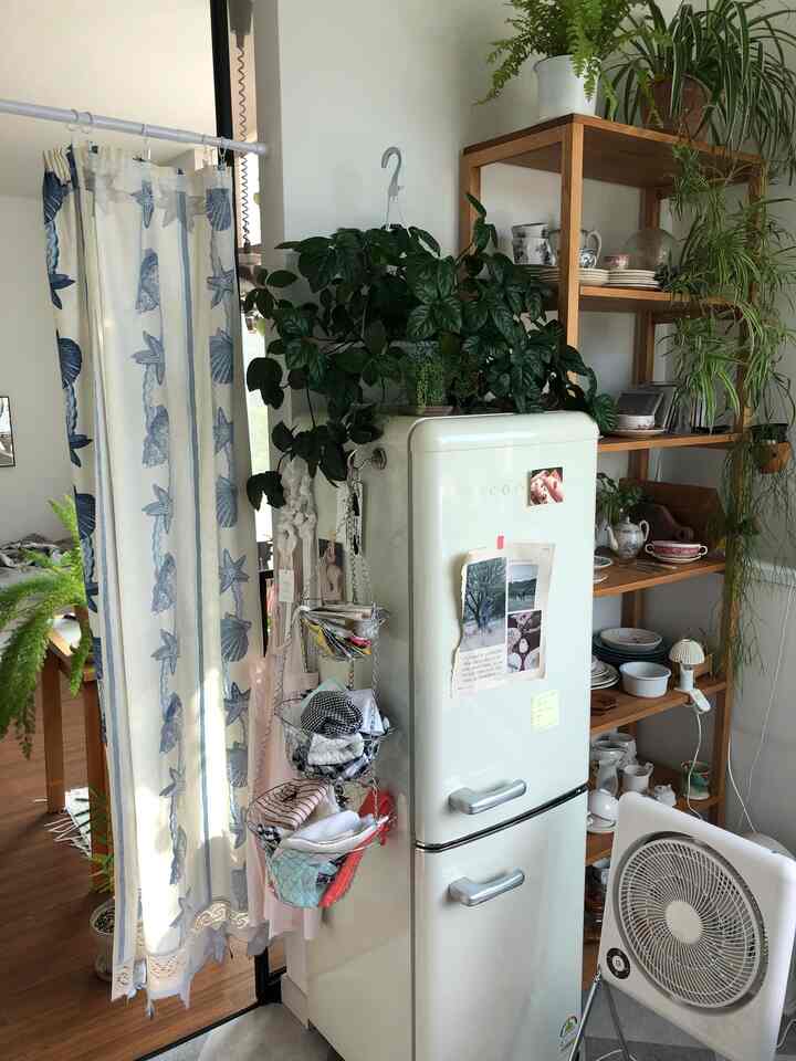 ホワイトとウッドトーンのキッチン空間、ヴィンテージ冷蔵庫と木製棚に多様な食器が整った雰囲気のあるインテリア