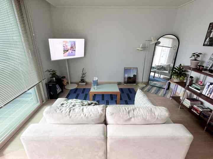 ホワイトとブルーの色調のリビング、ミッドセンチュリーモダン家具とブラインド、ラグが配置された落ち着いた雰囲気のインテリア