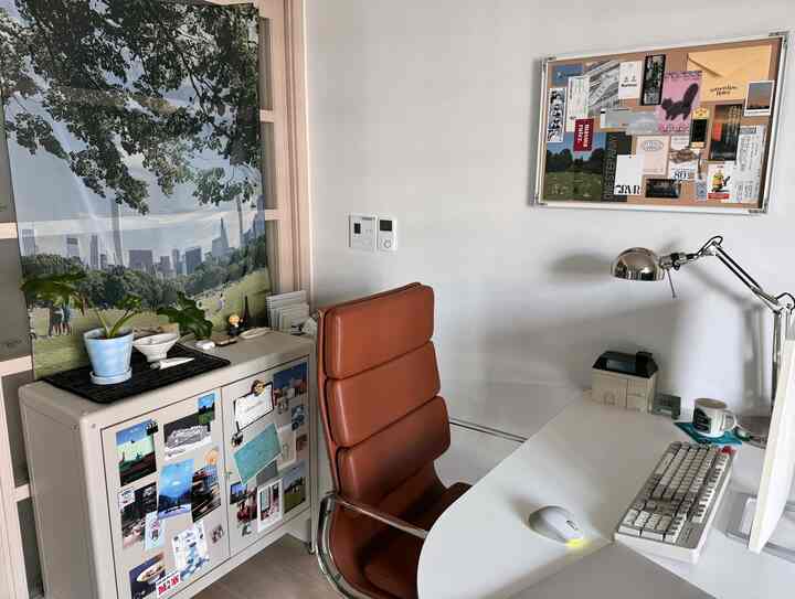 白と茶色のトーンのホームオフィス、机とオフィスチェア、額縁付きのボードが配置されたすっきりした作業空間