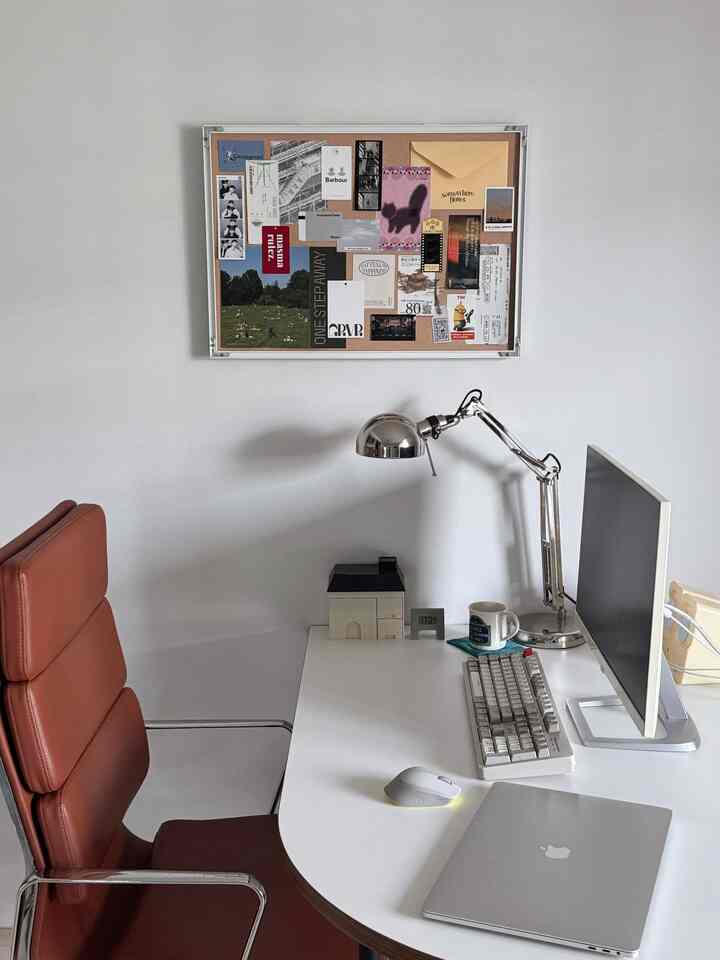 白を基調としたコンパクトなホームオフィス、ブラウンのミッドセンチュリーモダン風オフィスチェアとモダンなデスクランプが配置された印象的な空間