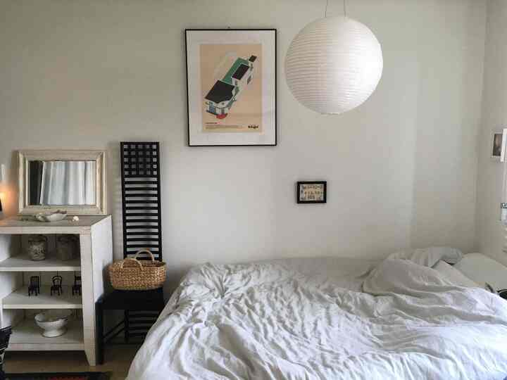 ホワイトトーンの寝室、大きく快適なベッドと額縁、自然な小物が調和するミニマルな空間