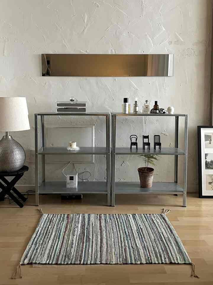 ナチュラルな色調のリビング、塗り壁と金属製の棚が配置されたシンプルで印象的な空間