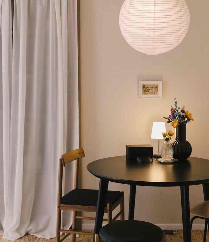 白と黒のトーンのキッチンスペース、木製の椅子と丸いダイニングテーブルが配置されたシンプルで温かみのあるインテリア