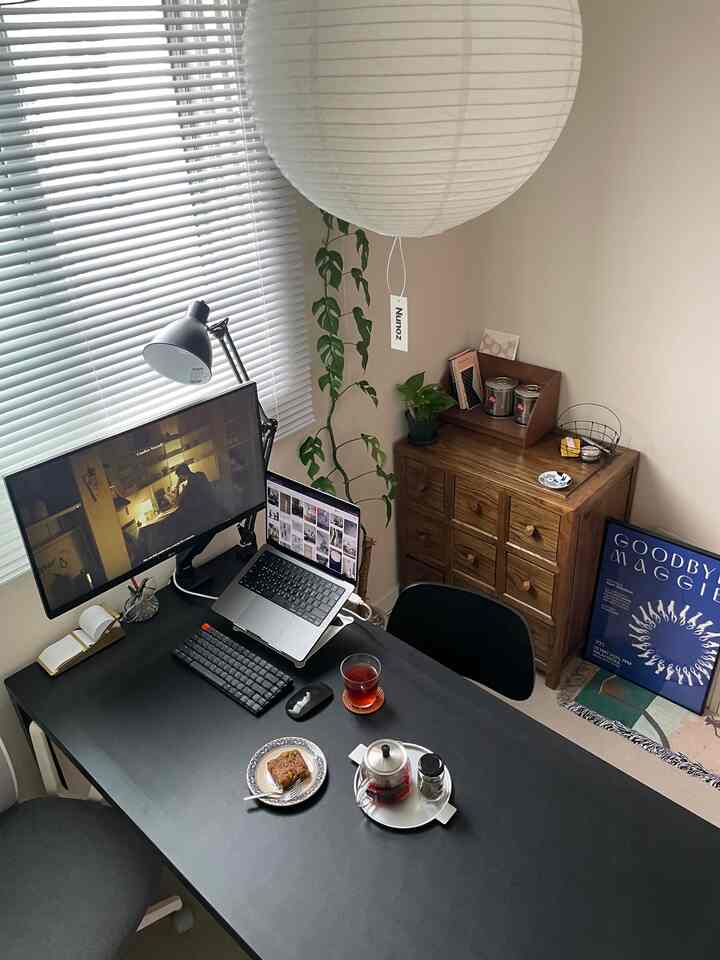 落ち着いた色調のリビング兼在宅勤務スペース、モダンなデスクと椅子、植物が配置された雰囲気のあるインテリア