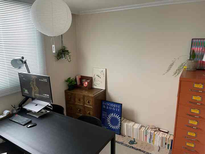 アイボリー色の壁と黒色のデスク、ブラウンの収納家具が配置された雰囲気のあるホームオフィス