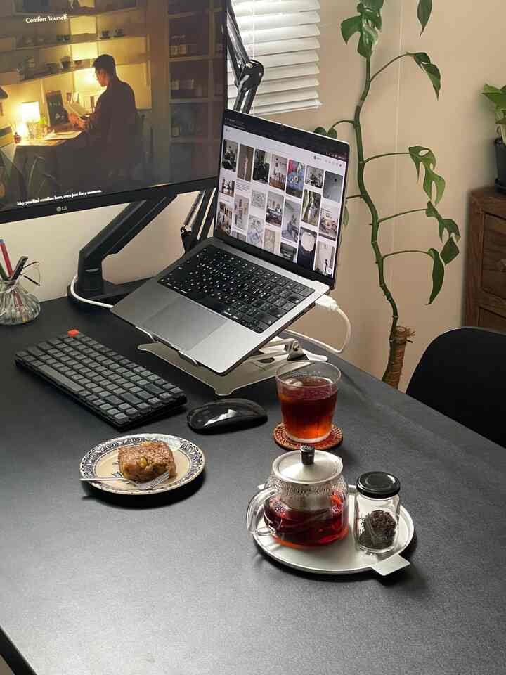 ダークグレーの落ち着いた雰囲気のホームオフィス、ノートパソコンとダイニングテーブルにティーとおやつが置かれた雰囲気あるインテリア