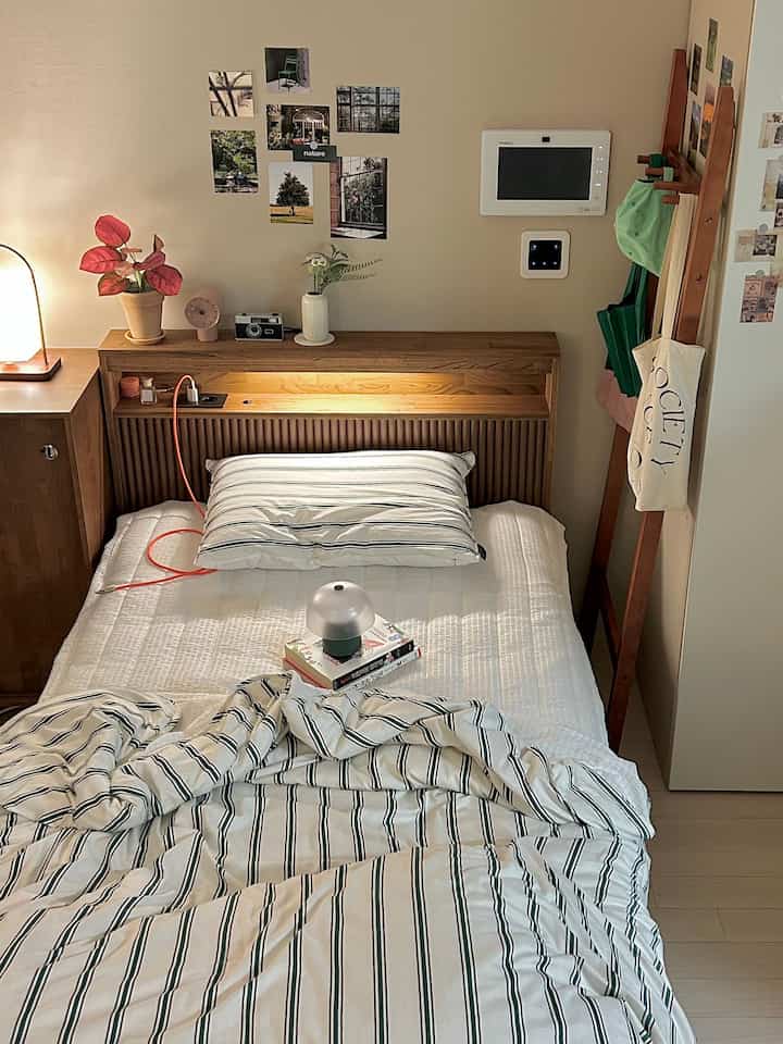 白と茶色のトーンの寝室、木製ベッドと枕が配置された居心地の良い一人暮らしの空間