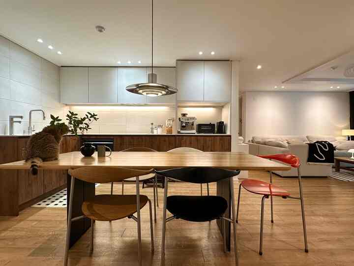 白とウッドトーンのモダンなキッチンダイニング、中央に大きなダイニングテーブルと椅子が配置された暖かく整った空間