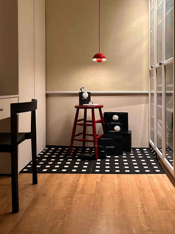 ナチュラルな木目床に赤いペンダントライトとテトリス柄の黒いラグがあるコンパクトな収納空間