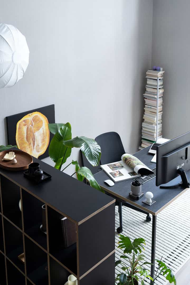 明るいグレーの壁とブラック家具が調和するホームオフィス、机と棚、植物が配置された整然とした作業空間
