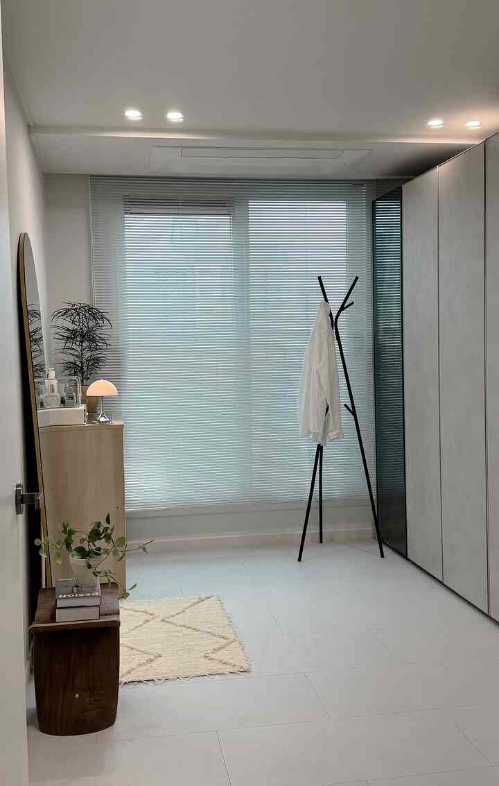 明るいベージュとナチュラルトーンのウォークインクローゼット、ビルトインクローゼットとコートラック、全身鏡が配置された清潔感のあるモダンな空間