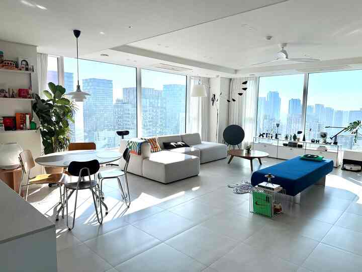 明るいホワイトトーンのリビング、大型ソファとブルーベンチが配置されたモダンで爽やかな雰囲気のインテリア