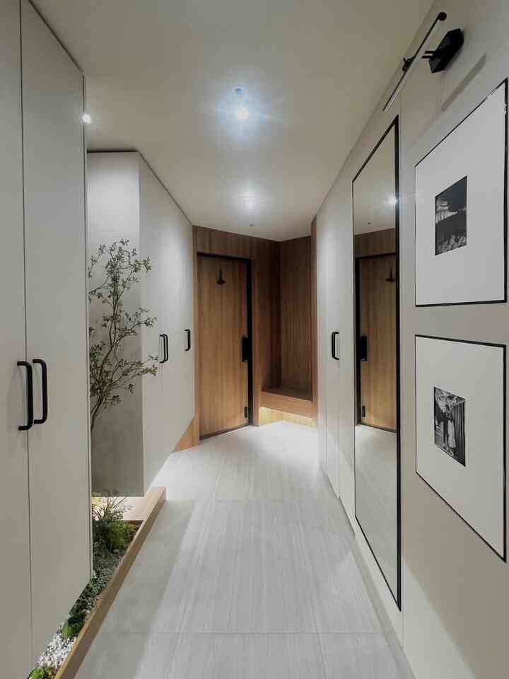 白と木目調が調和した洗練された玄関、ビルトインクローゼットと大型の鏡が配置された清潔感あるインテリア