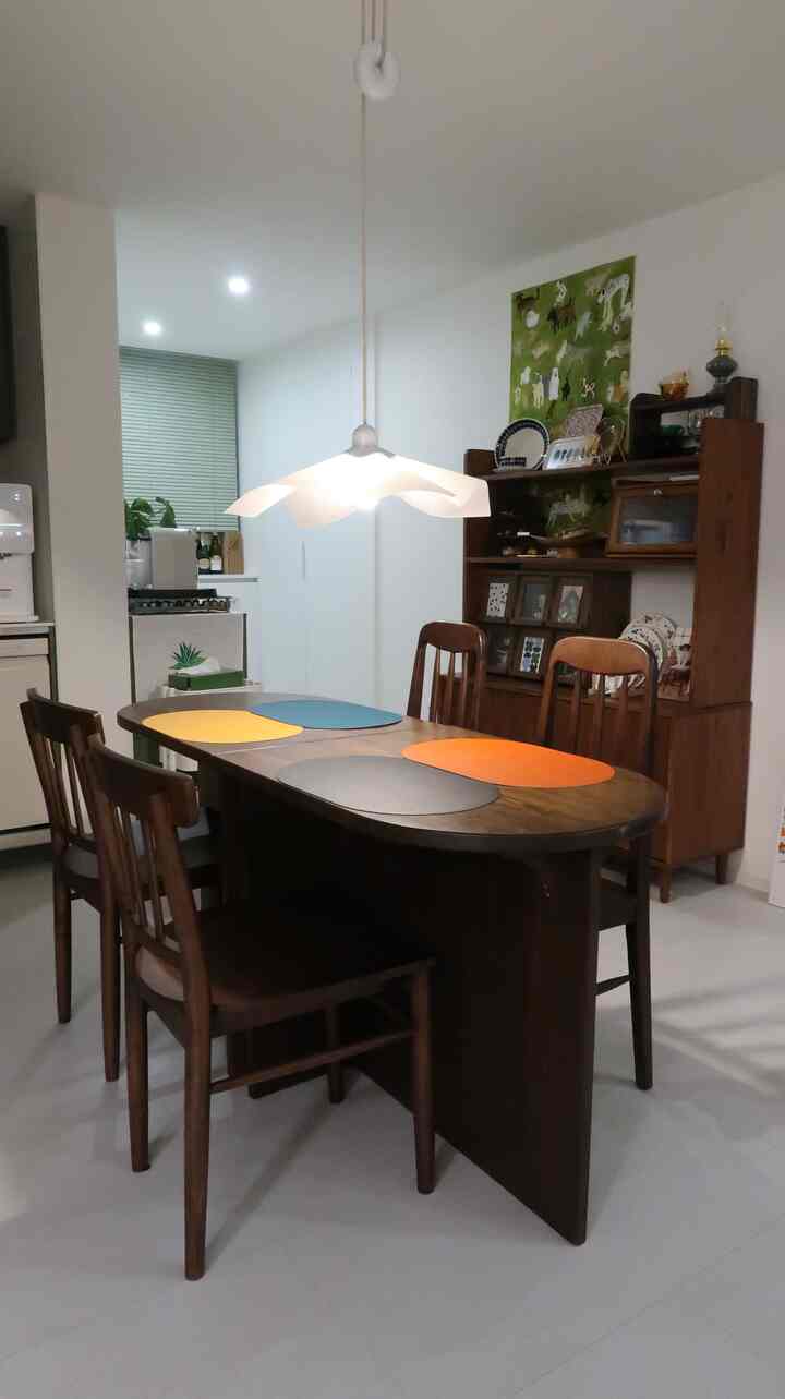 ナチュラルカラーのダイニング、ヴィンテージ木製ダイニングテーブルと4脚のチェア、ペンダントライトが配置された雰囲気のあるインテリア