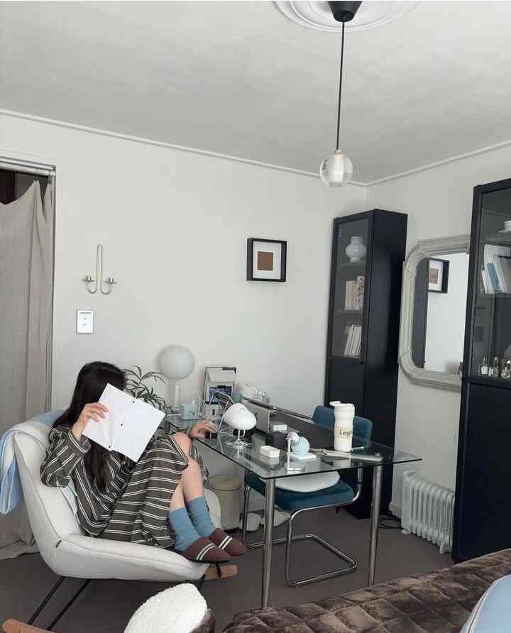 白黒のトーンのリビング、ガラステーブルとアームチェアが配置されたシンプルでモダンな空間