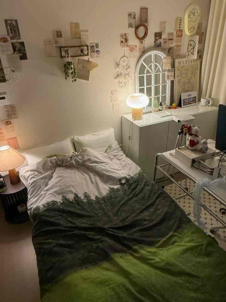 暖かいベージュと木目調が調和するヴィンテージ感あふれる寝室、壁にはポストカードとヴィンテージポスターがギャラリーのように飾られた居心地の良い空間