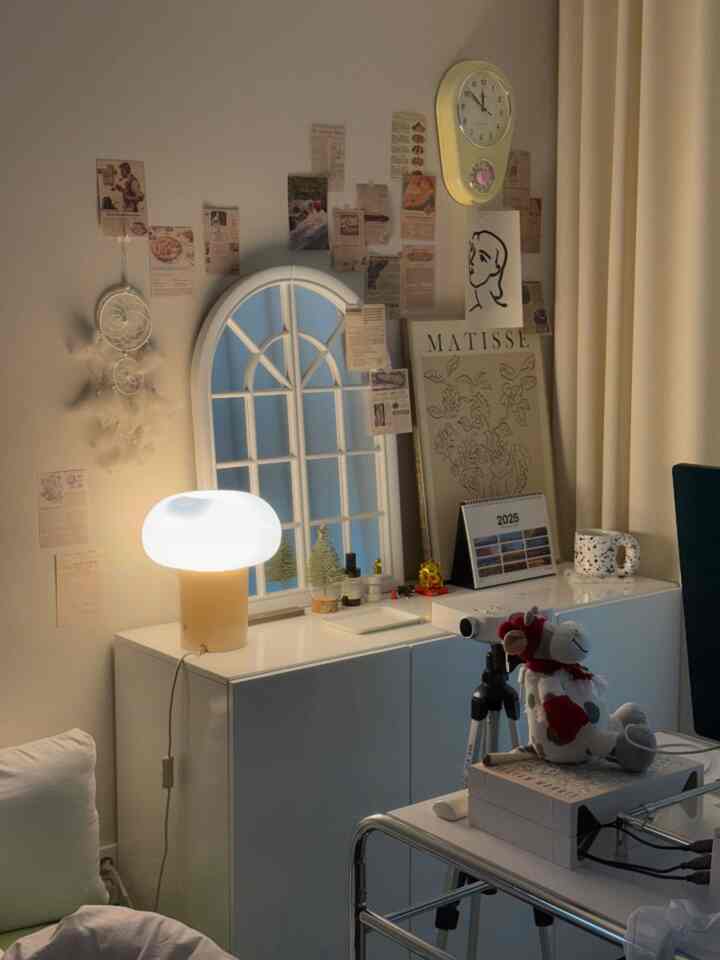 白とベージュの色調のリビング、テーブルランプと時計、額縁が配置された自然な雰囲気のインテリア