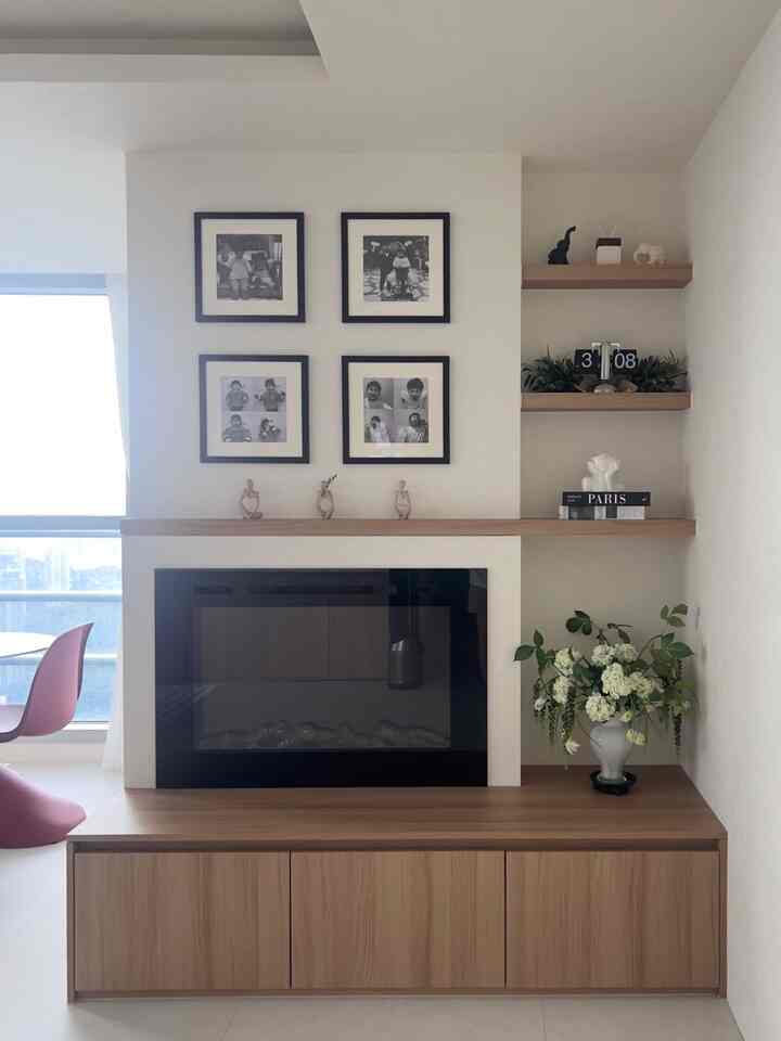 ナチュラルカラーの壁暖炉と額縁が配置されたシンプルでモダンなリビングスペース