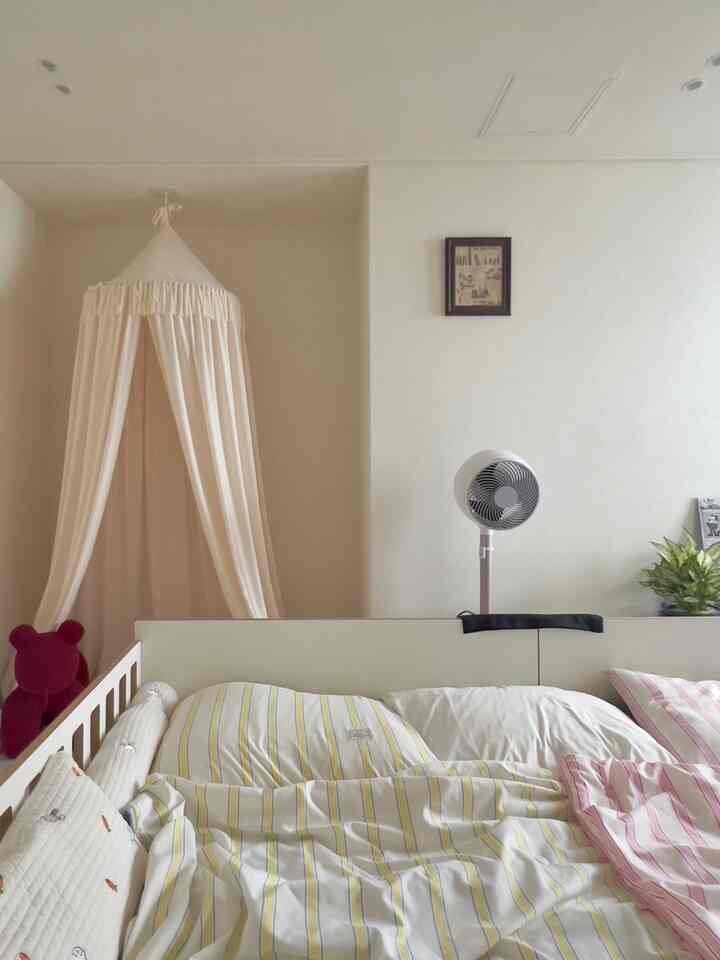 明るいベージュとホワイトトーンの子供部屋、子供用ベッドと天井から吊るされたキャノピーがある、清潔で温かみのある雰囲気のインテリア