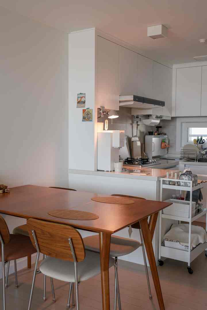 ナチュラルな木目調と白を基調としたキッチン空間、ミッドセンチュリーモダンのダイニングテーブルと隙間収納が配置された雰囲気のあるインテリア